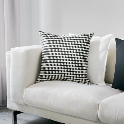 Large white couch with black/white checkered pillow, stylish & cozy.