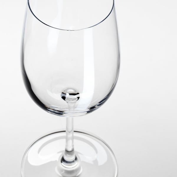 A clear, empty wine glass shown in close-up, highlighting its smooth stem and shiny, transparent bowl.