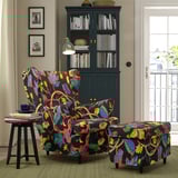 STRANDMON floral chair & ottoman, dark fabric, colourful leaves, near lamp & bookshelf.