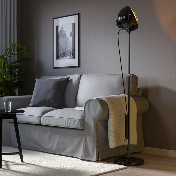 Black floor lamp beside gray sofa, providing focused light in modern living room.