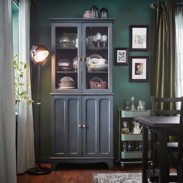 Cozy dining room with green walls, dark wood furniture, a black lamp, and framed photos.