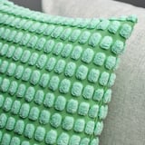 Green cushion cover with soft, textured pattern; shows quality and tactile detail.