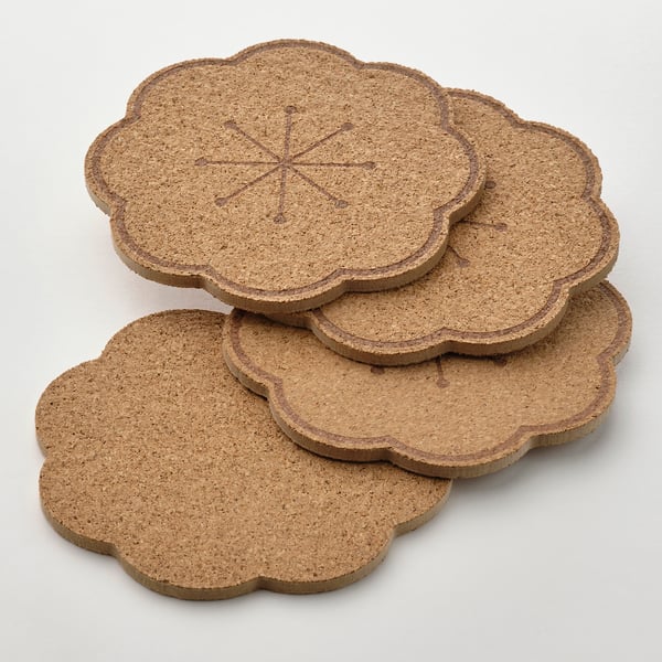 Four round cork coasters with scalloped edges stacked neatly, showing natural texture and durable quality.