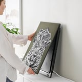 Person holding a SYMFONISK picture frame speaker with interchangeable art panel.