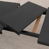 Black extendable dining table with metal frame, shown with extension leaf stored underneath. Adjusts to seat 4-6 people.