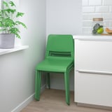 Bright green stackable chair against white cabinets, perfect for indoor use.