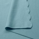 Soft light blue recycled polyester blanket, folded neatly, showcasing its smooth texture.