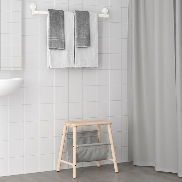Wooden stool, cloth pouch, towels, sink in minimalist bathroom.