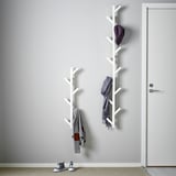 Wall-mount coat rack with two sections, holding jackets, scarves, and a cap, by doorway.