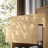Wooden drawer unit with two visible drawers, one partly open, in a light, natural wood finish. Constructed with a simple, clean design.