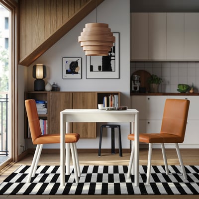 Modern dining area with TONSTAD table, orange chairs & black/white rug.