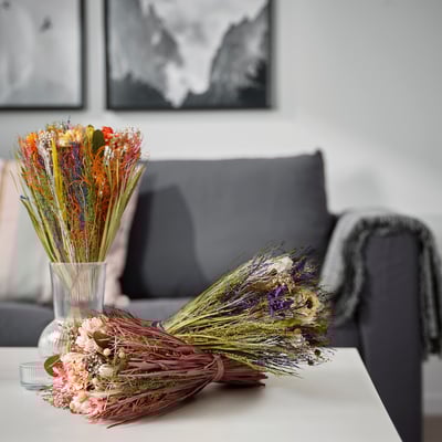 Dried plant bouquet on table, gray couch, black & white art, colorful flowers.