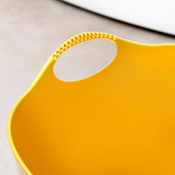 Bright yellow flexible laundry basket with sturdy handles, placed on a light-colored surface.