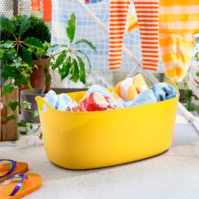 Yellow flexi laundry basket with colorful clothes. Sturdy handles, indoor/outdoor use.