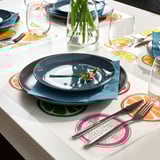 Bright place mats in vivid patterns enhance table setting, creating cheerful atmosphere. Made of durable plastic, easy to clean.