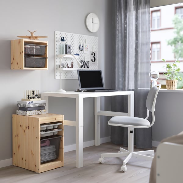 TROFAST desk, storage units, swivel chair, clock, lamp, laptop - neat, modern home office setup.