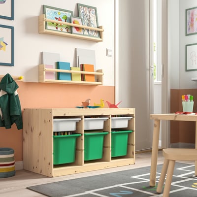 Kids room with TROFAST light wood storage, green bins, and shelves holding colorful toys and books.