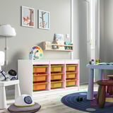 Childrens room with TROFAST storage unit featuring orange plastic boxes and white frame. The large, low unit holds toys, books, and has playful decor.