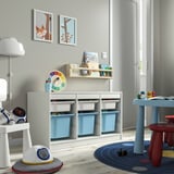 Playroom with TROFAST storage units with blue bins, colorful clock, and childrens art.