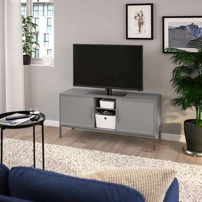 Modern living room with TULLSTORP tv stand, flat screen, cushioned seating, black side table, white rug, plants.