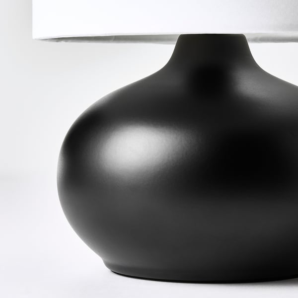 Modern black table lamp with smooth, rounded base and white lampshade.