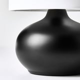 Modern black table lamp with smooth, rounded base and white lampshade.