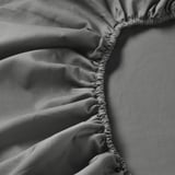 A close-up of soft, high-quality bedsheet fabric, featuring delicate stitching and smooth texture.