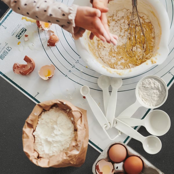 Example image baking scene: white mixing bowl, eggshells, measuring spoons, eggs, flour bag, UPPFYLLD white plastic measuring cups.