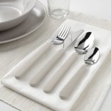 Silverware set: fork, knife, spoon, teaspoon on beige napkin, anti-slip handles.