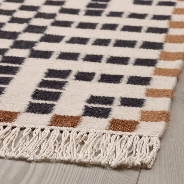 Geometric wool rug with fringe, high-quality handmade craftsmanship, soft texture.