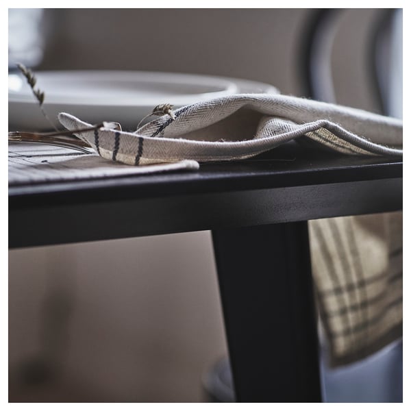 A rolled napkin sitting on a table, featuring earthy tones and a rustic design made of cotton and jute.