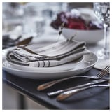 Dining table with folded VÅRARV cotton napkins on plates and cutlery.