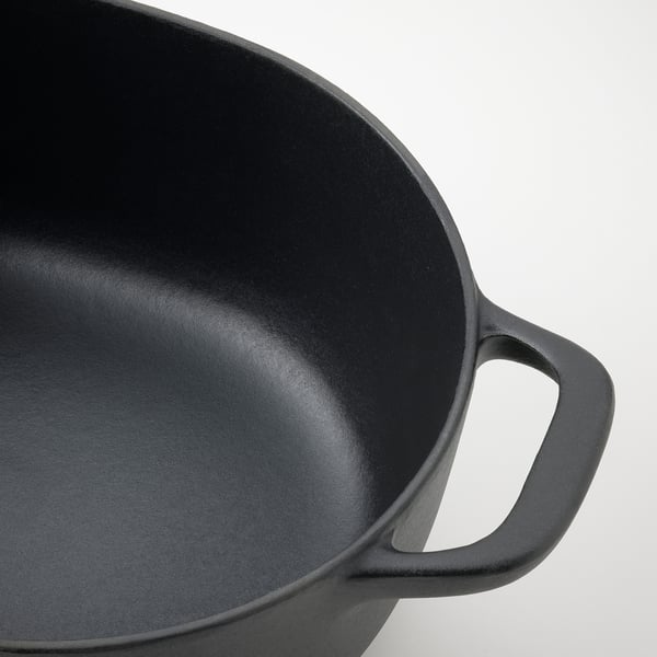 Black cast iron pan with smooth, even interior surface and sturdy handle, perfect for cooking.