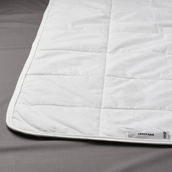 A soft, white duvet lays neatly on a bed, showcasing its smooth fabric and quality construction.