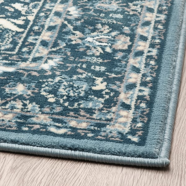 Vintage-inspired rug with intricate blue patterns on wooden floor, high-quality and durable, classic-modern appeal.