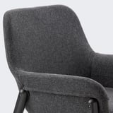 Close-up of a grey fabric armchair, showcasing high-quality upholstery and sturdy black metal legs.