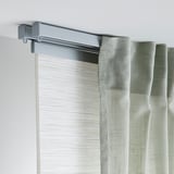 Gray curtain rail mounted on white wall, supporting light green curtains. Easy to assemble and flexible for tricky spaces.