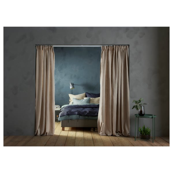A cozy bedroom with a grey bed, light brown curtains, and green side tables.