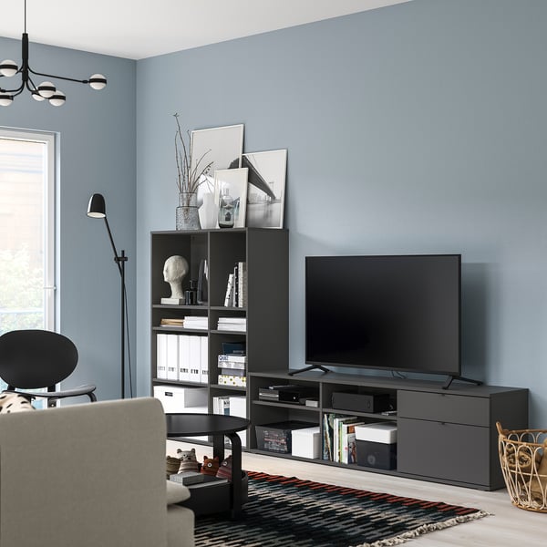 Modern living room with blue walls, black tv unit, white armchair, striped rug, and floor lamp.