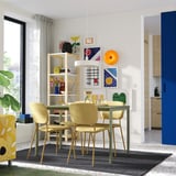 Modern dining room with VIHALS table, beige chairs, art, plants, dark rug.