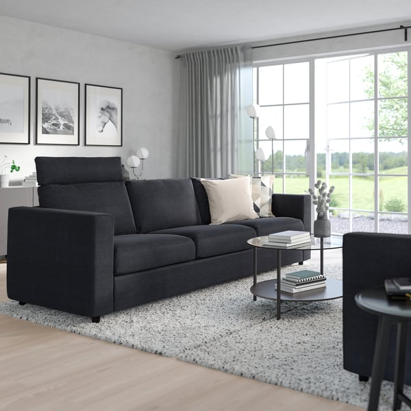 Modern living area with gray VIMLE sofa, black coffee table, and windows overlooking greenery.