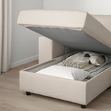 Sofa with open storage compartment, pillows, and cozy blanket inside.