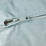 Close-up of high-quality zipper on light blue corduroy fabric.