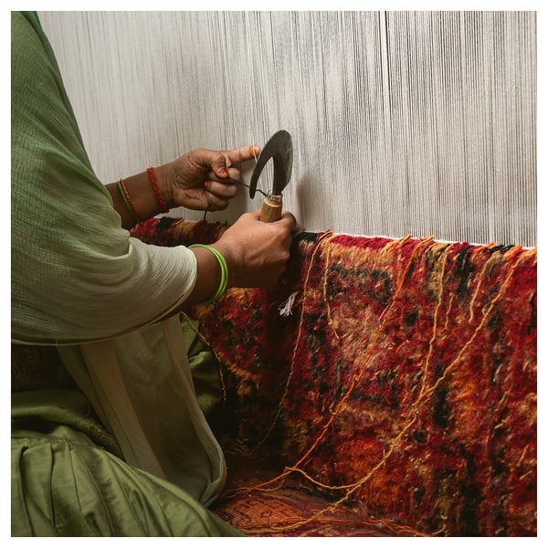 Person weaving colorful, handmade rug.