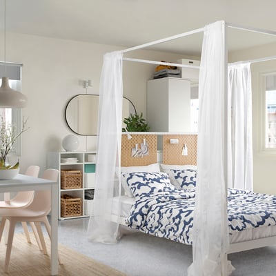 Modern bedroom with VITARNA four-poster bed, blue bedding, pegboard, and dining area.