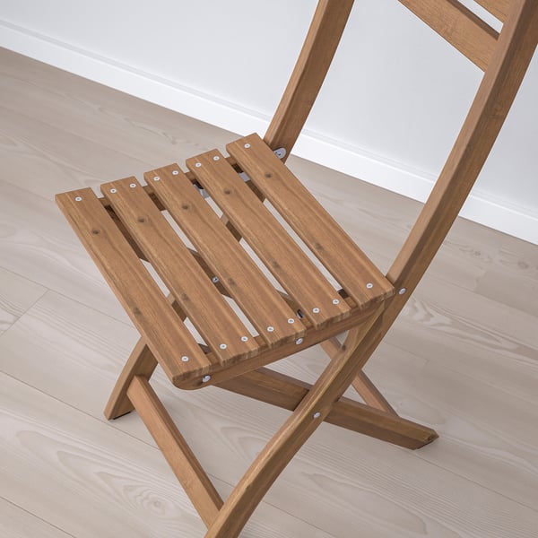 Opklapbare houten stoel op lichte houten vloer, gemaakt van duurzaam acaciahout, van bovenaf gezien.