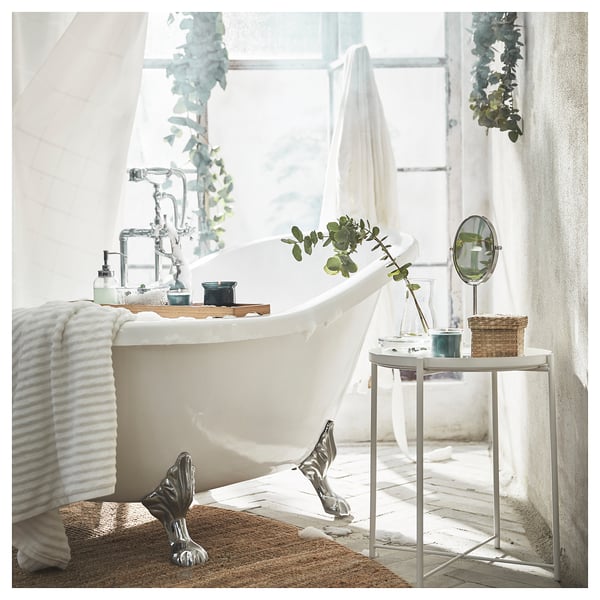 Elegante badkamer met wit bad op pootjes, zilveren kraan, belgravia bijzettafel met spiegel, vazen en fris groen.