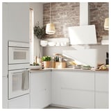 Moderne keuken met witte kasten, RVS oven, bakstenen muur, verlichting en aanrechtartikelen.