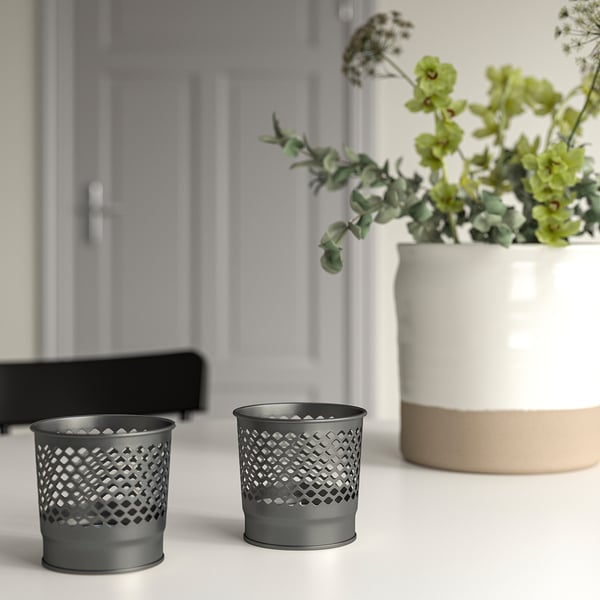 Zwarte kandelaars, planten, wit oppervlak, grijze deur.