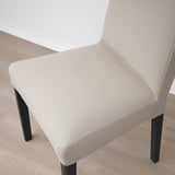 Neutraal getinte moderne stoel met strakke zwarte poten, met hoogwaardige bekleding en eigentijds design.